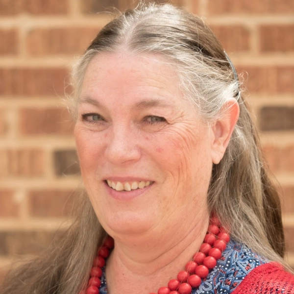 Heidi Cross-persno-smiling-wearing-red-necklace woman smiling with long hair and wearing a red necklace